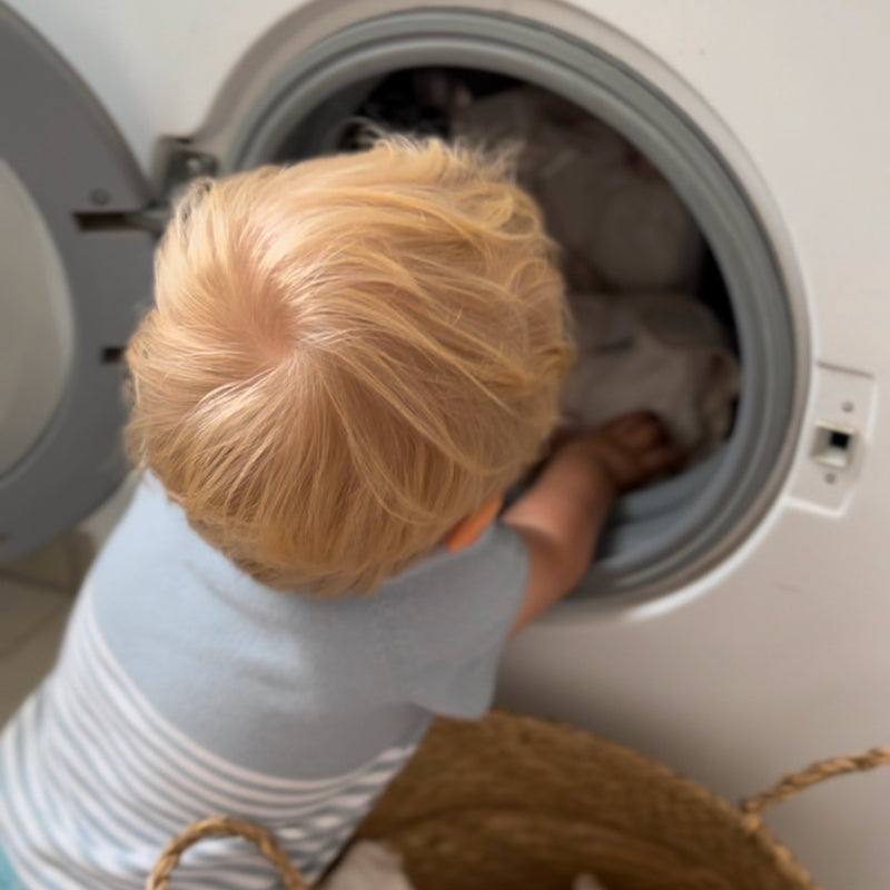Windelservice oder selber waschen Kind steckt Judes Windeln in Waschmaschiene
