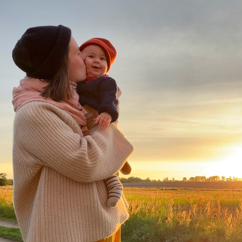 Judes mamá besa al bebé en el campo al atardecer