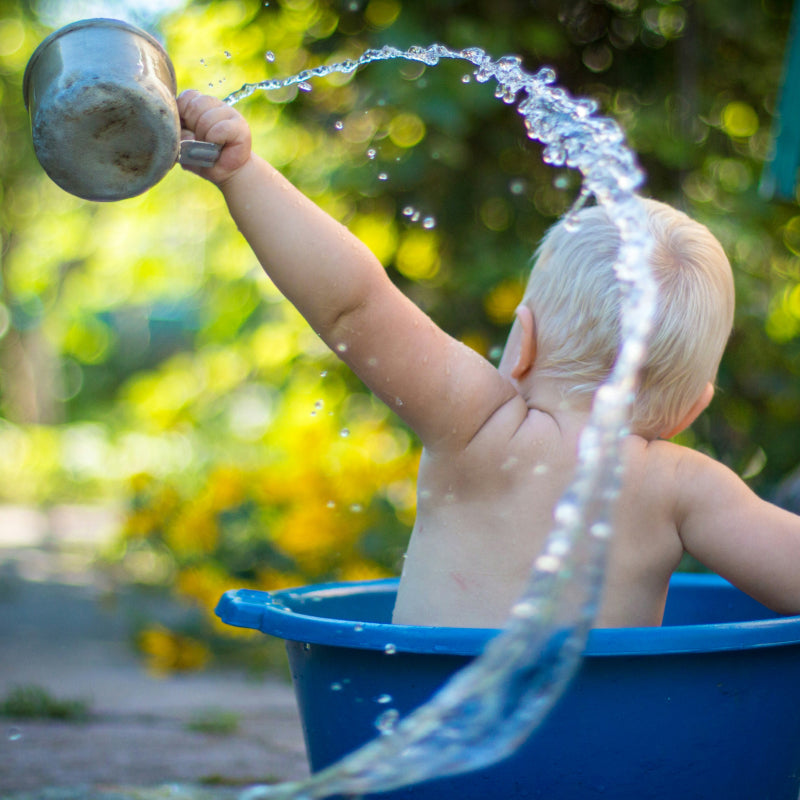 Judes bébé éclabousse de l’eau dans un bol soin de la peau de bébé