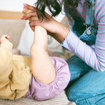 Mama playing with baby wearing cloth diapers from Judes. Judes are designed to support healthy hip development and free movement.